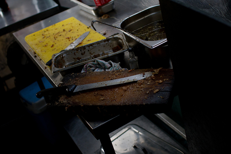 cutting boards of a street vendor, large knife in the foreground, bits of food