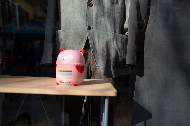 shop window display, pink plastic toy with fashionable grey clothing in the background