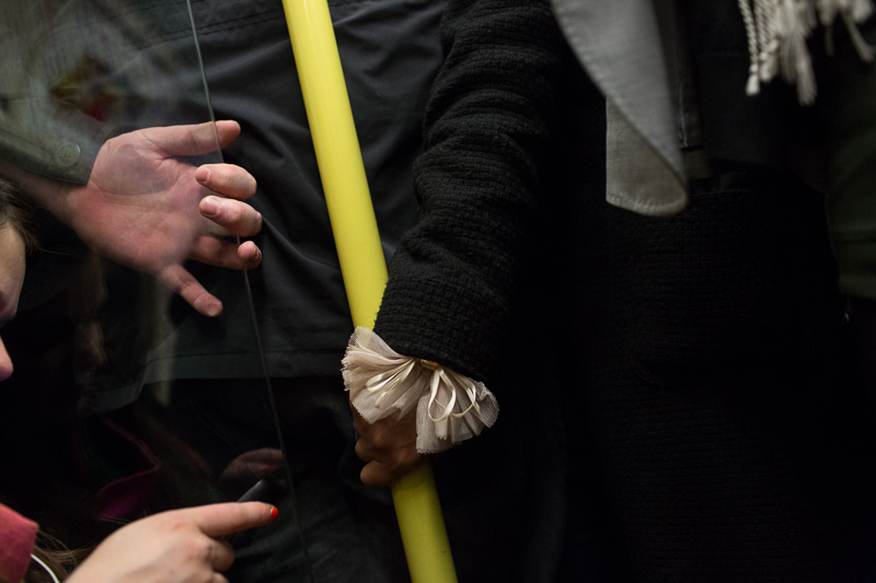 hands of commuters on the london underground, a woman's hand holding onto railing, man's hand holding onto the glass pane, and a woman's hand holding a smartphone