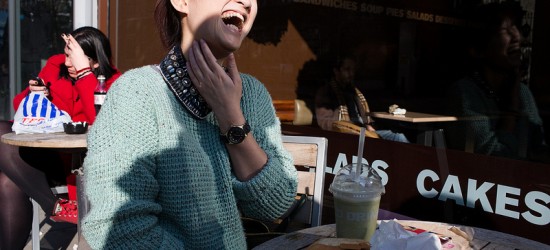 asian woman laughing, sitting at an outside table